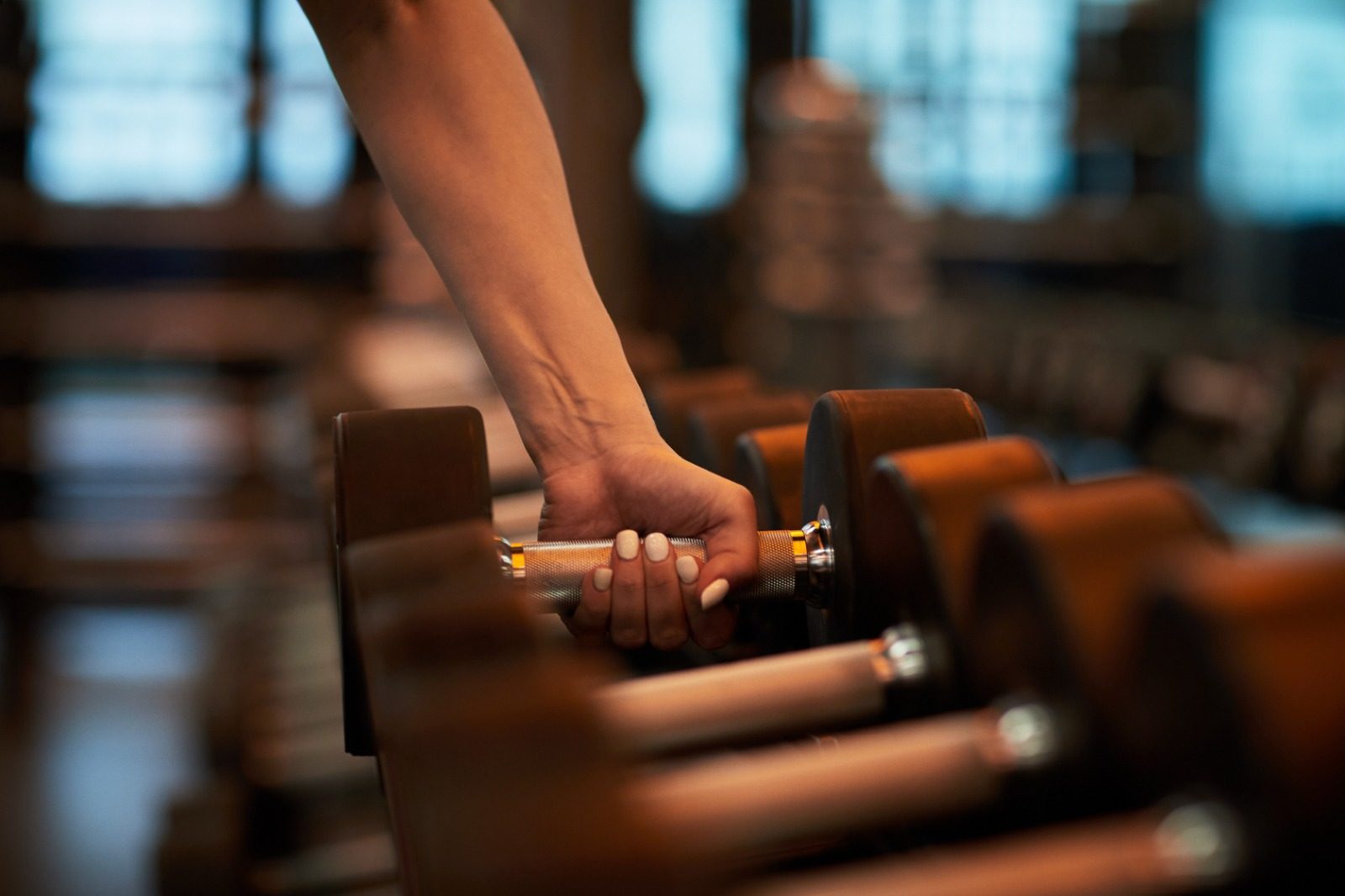 Woman taking a dumbbell from the rack