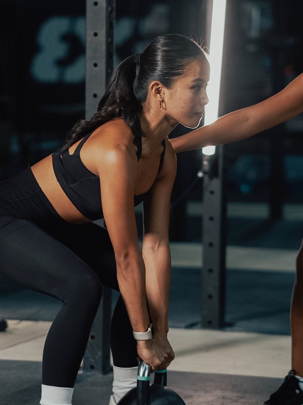 Personal trainer coaching a woman with a kettlebell